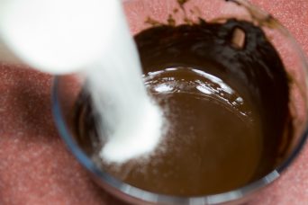 بعد ذوبان خليط الشوكولاتة وتركه يبرد لخمس دقائق، أضف السكر وأخلط لثلاثة دقائق بالسرعة المتوسطة